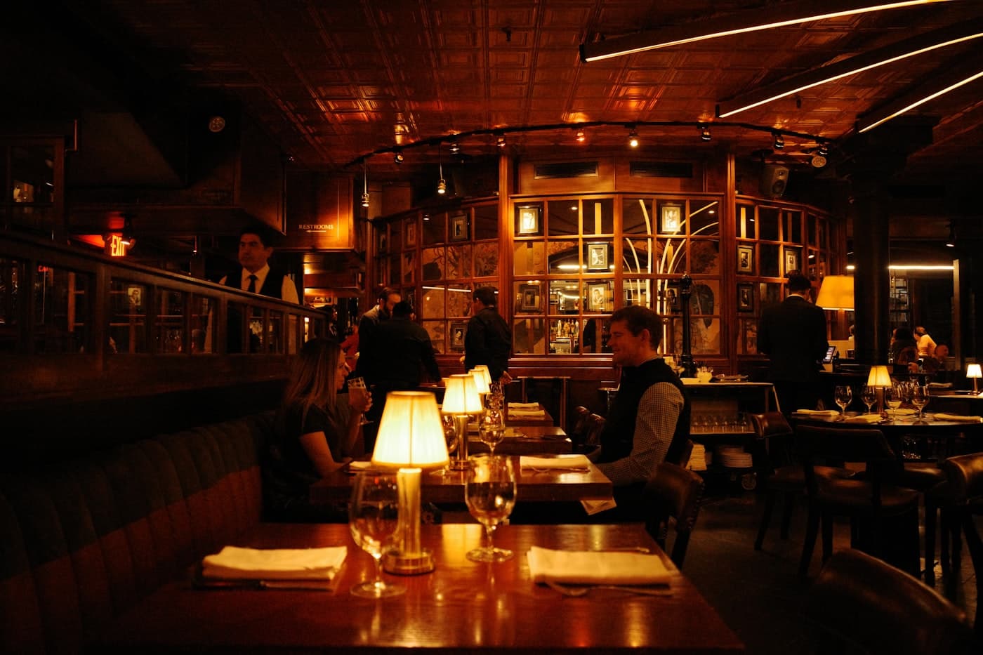 Salão de restaurante à meia-luz, com abajures acesos nas mesas